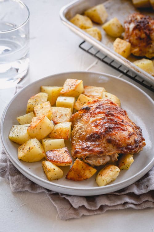 These baked mustard chicken thighs and potatoes are a flavorful and satisfying comfort meal, quick enough to make on a busy weeknight! #chickenthighs #roastchikenthighs