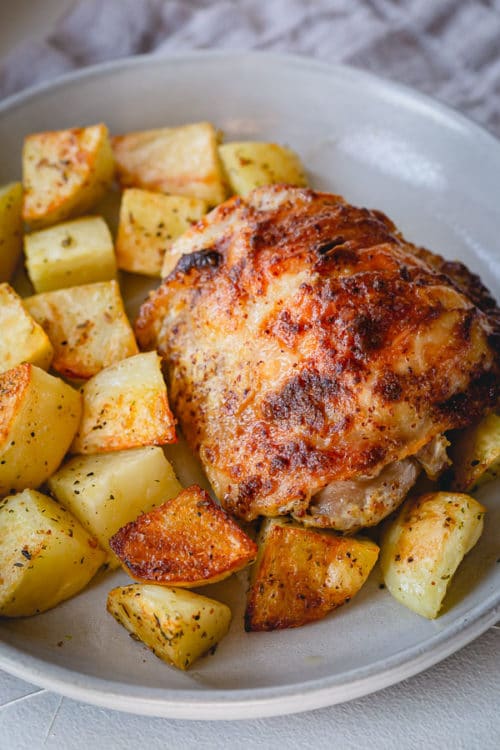 These baked mustard chicken thighs and potatoes are a flavorful and satisfying comfort meal, quick enough to make on a busy weeknight! #chickenthighs #roastchikenthighs