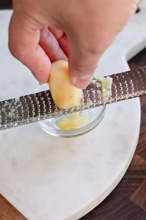 Grating fresh ginger on a microplane grater.