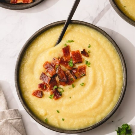 Cream Cauliflower soup in a bowl with bacon topping.