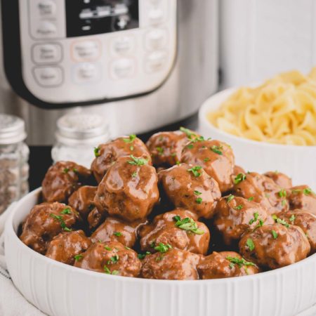 Swedish meatballs in a large serving bowl with Instant Pot in the background.