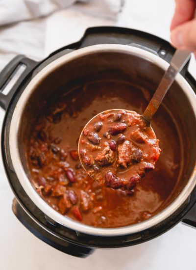 A ladle of chunky chili over Instant Pot of chili.