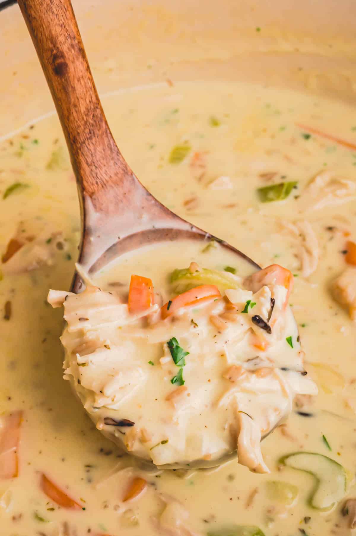 Creamy turkey and rice soup scooped in a wooden paddle.