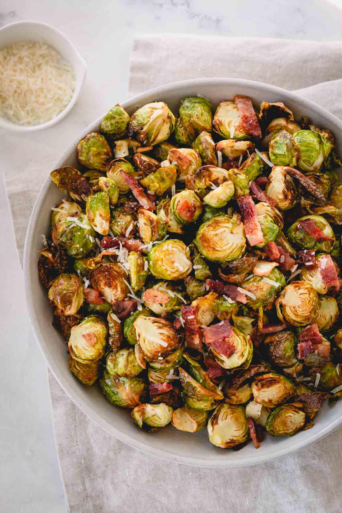 a bowl of crispy brussels sprouts with bacon and parmesan cheese.