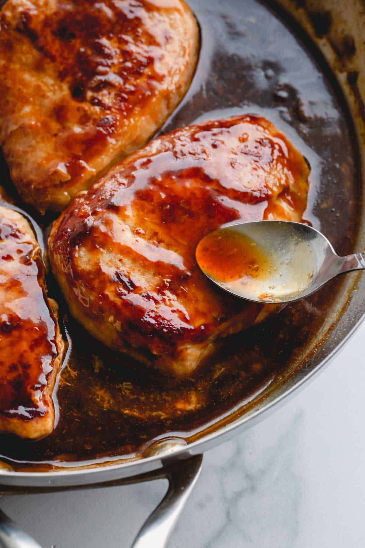 pork chops covered in honey glaze in a skillet.