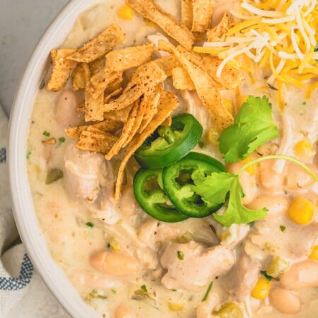 a bowl of white chicken chili with cheese and jalapenos.