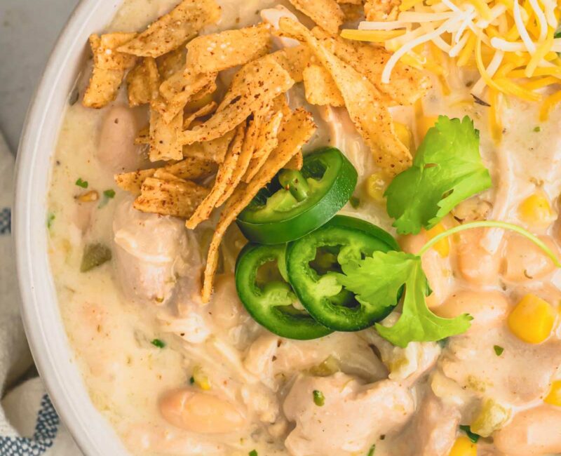 a bowl of white chicken chili with cheese and jalapenos.