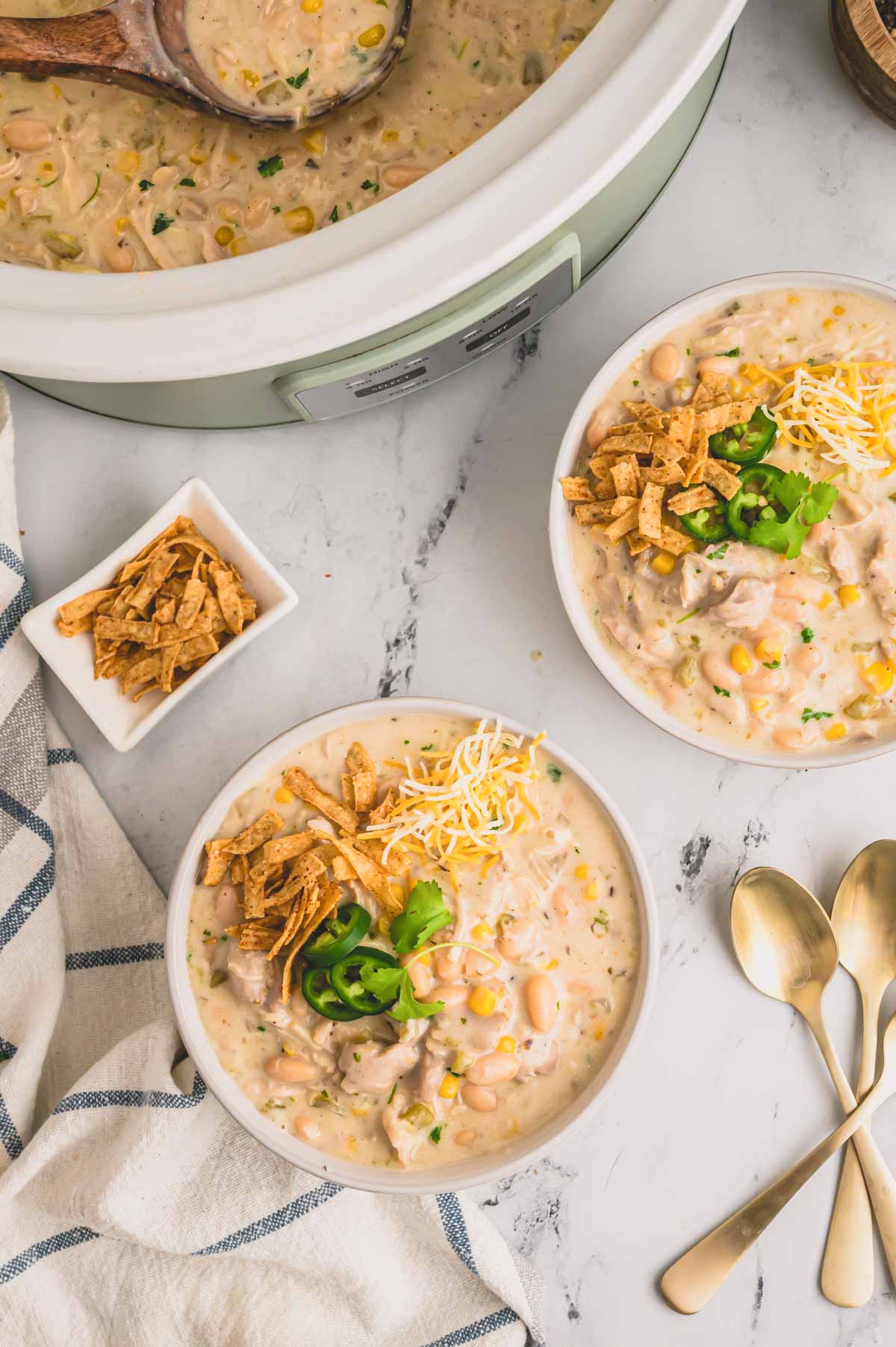 two bowls of white chicken chili with cheese and jalapenos.