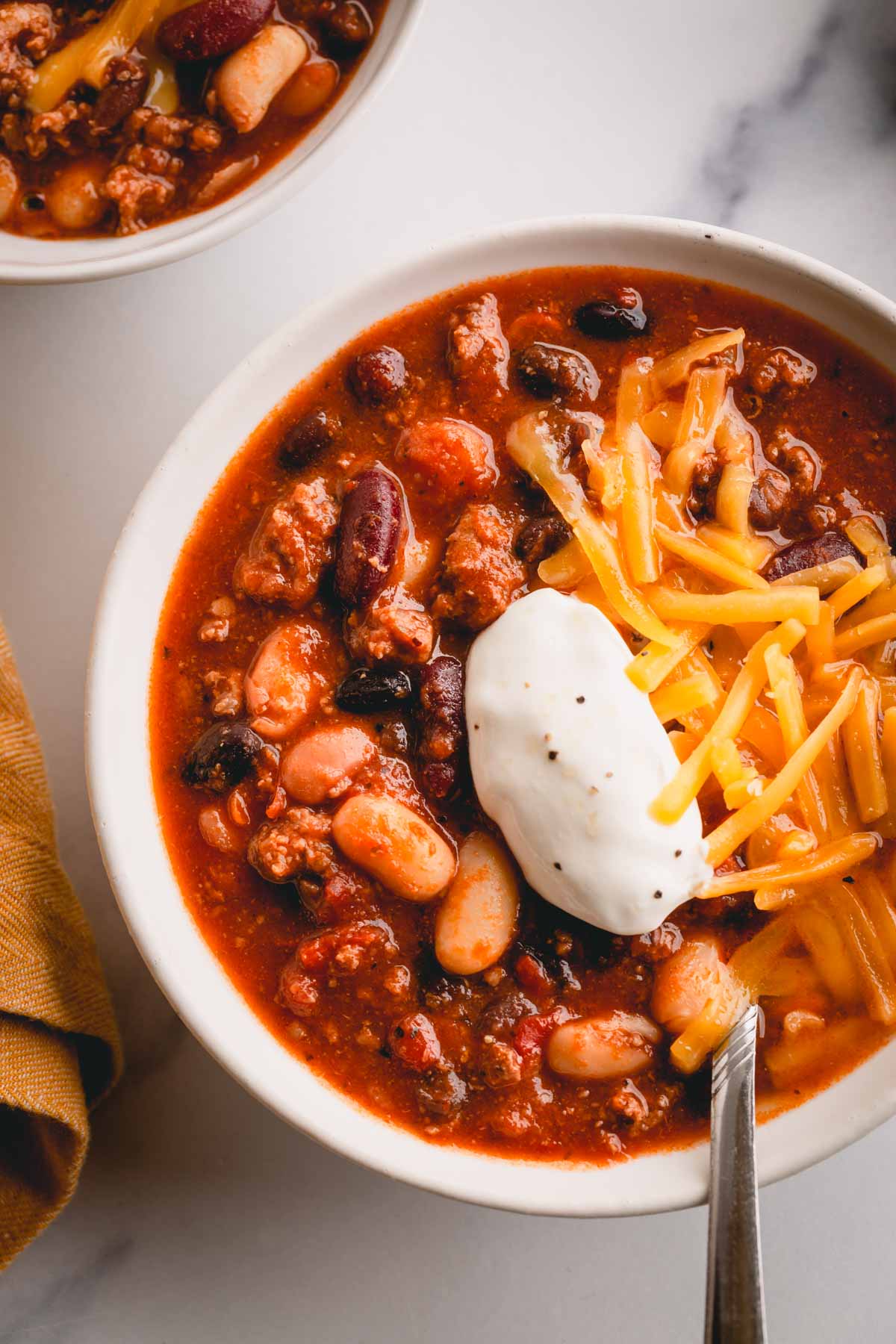 a bowl of chili with sour cream and cheese. 