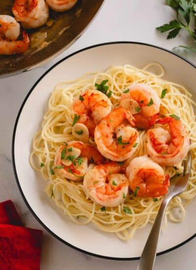 A plate of garlic butter shrimp pasta with a fork.